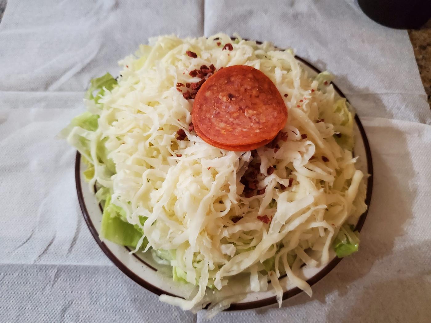 A Pizza Glen house salad buried under a mound of shredded cheese with a slice of pepperoni on top